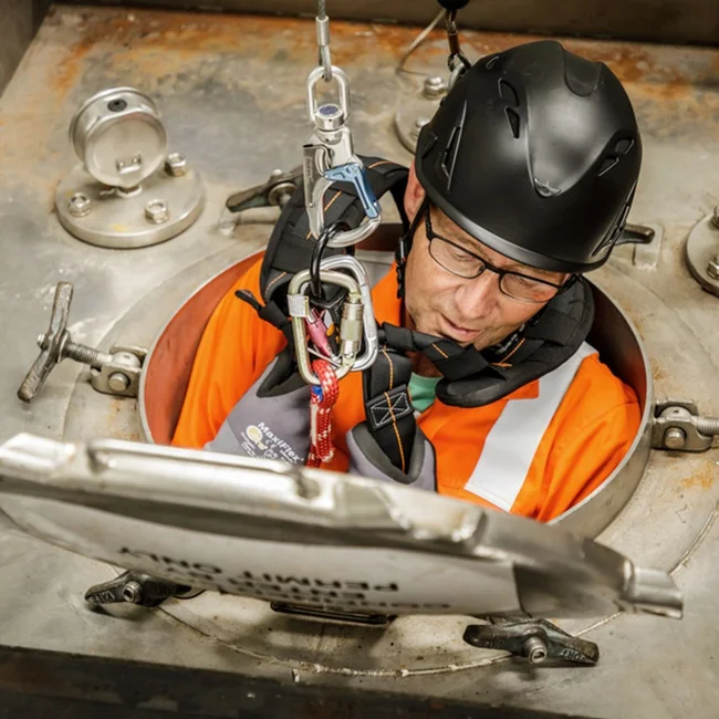 Technician in safety gear performing tasks.